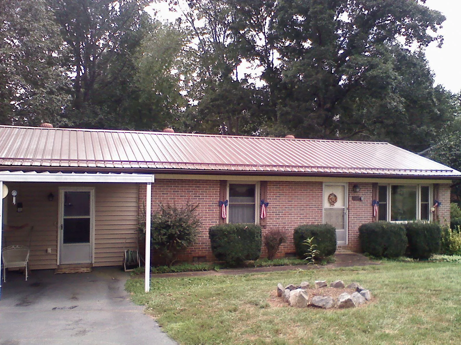 Bronze metal roof and carport on a brick ranch home — Roof Repair work by our crew in Creston